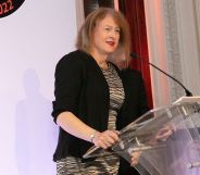 Master Victoria McCloud recieving the Outstanding Achievement Award at the National Paralegal Awards 2022. She is standing at a podium wearing a dress and dark cardigan.