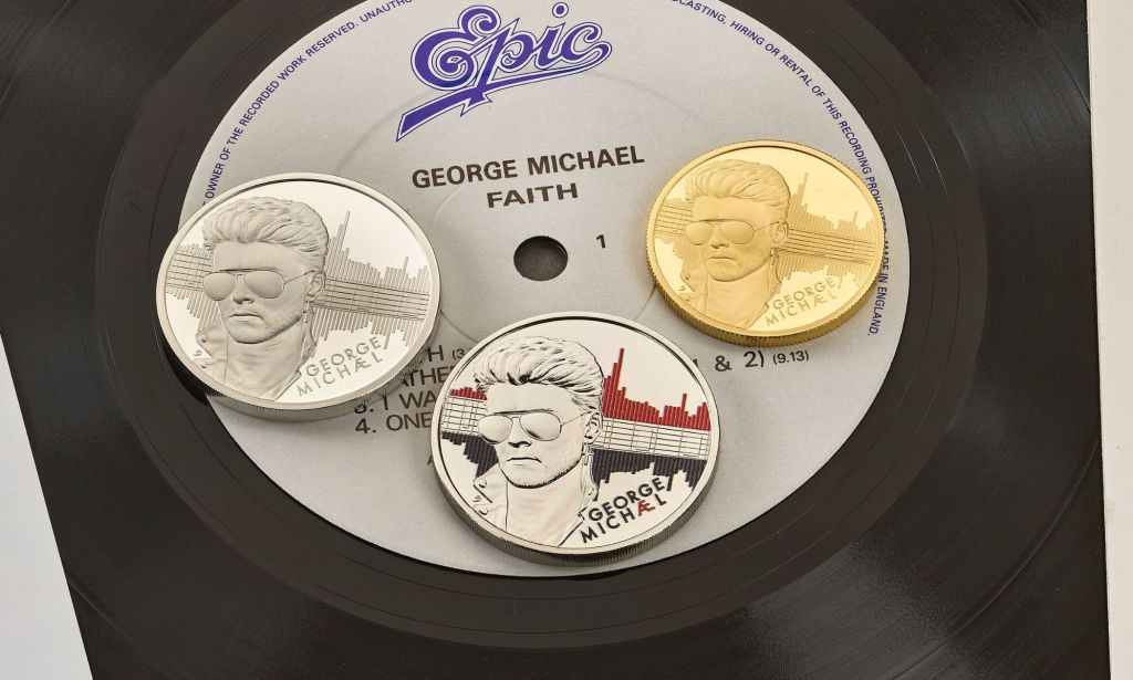 Three coins with George Michael's faced engraved in them on top of a record.