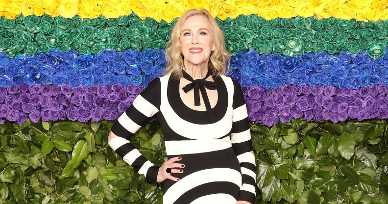 Catherine O'Hara poses in front of a rainbow background