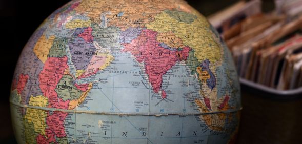 Photo of a globe with hand pointing at various countries