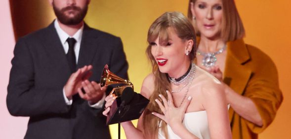Taylor Swift onstage with Celine Dion at the 2024 Grammys. Swift is in the foreground and has her back to Celine Dion.