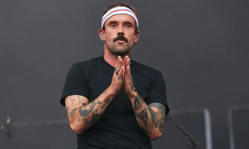 A man wearing a headband puts his hands together during a gig.