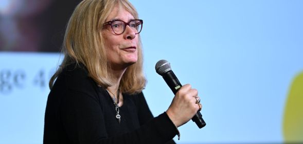 Lucy Sante speaks at a panel event, with a microphone in hand