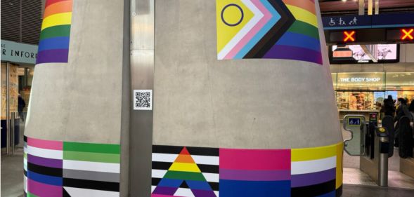 A pillar with stickers of LGBTQ+ flags across it at London Bridge station marking LGBT+ History Month