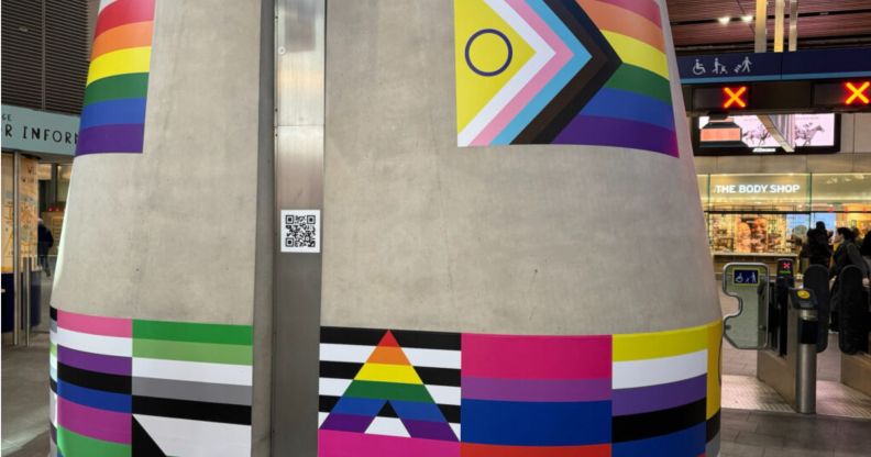A pillar with stickers of LGBTQ+ flags across it at London Bridge station marking LGBT+ History Month