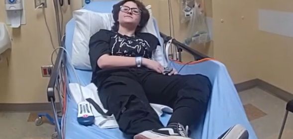 Nex Benedict lying down in a blue hospital bed facing the bodycamera.