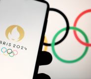 In this photo illustration a 2024 Summer Olympics (Paris 2024 Olympic Games) logo is seen on a smartphone and Olympic rings on a computer screen in Athens, Greece on April 19, 2023. (Photo illustration by Nikolas Kokovlis/NurPhoto via Getty Images)