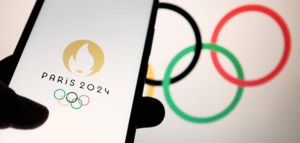 In this photo illustration a 2024 Summer Olympics (Paris 2024 Olympic Games) logo is seen on a smartphone and Olympic rings on a computer screen in Athens, Greece on April 19, 2023. (Photo illustration by Nikolas Kokovlis/NurPhoto via Getty Images)