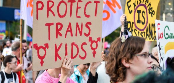 Protester holds a sign reading "protect trans kids"