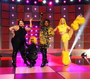 Image shows four Drag Race queens on stage doing the girl group challenge, wearing flamboyant costumes. One is high kicking
