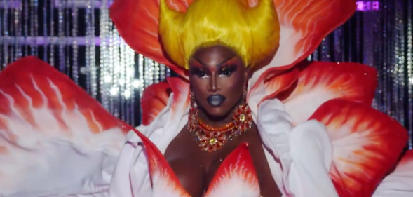 Photo shows a close up on Sapphira Cristal on Drag Race Season 16 episode 7, she is Black and has a yellow wig and white and red dress.