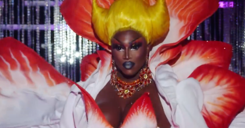 Photo shows a close up on Sapphira Cristal on Drag Race Season 16 episode 7, she is Black and has a yellow wig and white and red dress.