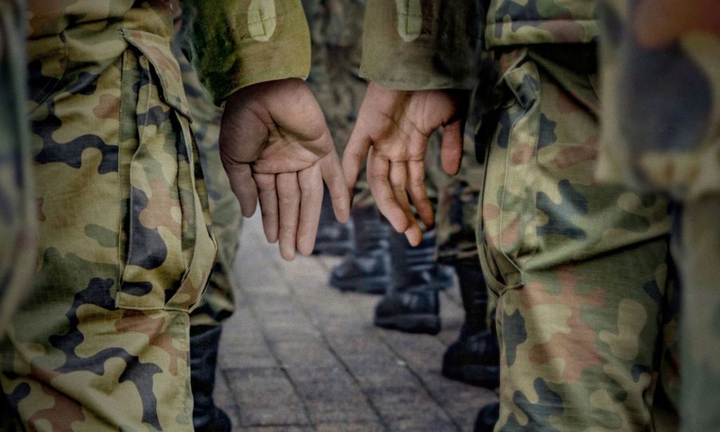 This is an image of two military men's hands touching each other. 