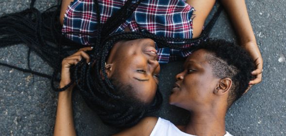 Two black lesbians lying down opposite each other