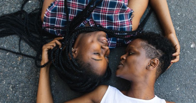 Two black lesbians lying down opposite each other