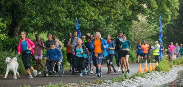Group of people run through a green area to illustrate Parkrun event