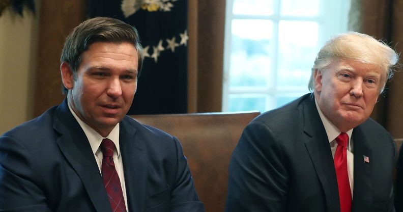 Republican politicians Ron DeSantis and Donald Trump sit side by side in the White House