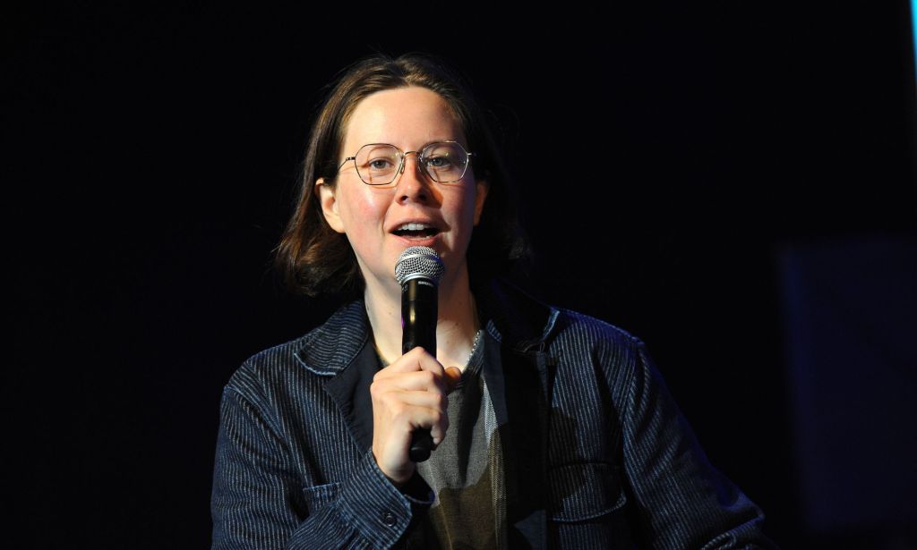 Comedian Chloe Petts, who appears on Hannah Gadsby's Netflix special Gender Agenda, wears dark clothing while speaking into a microphone