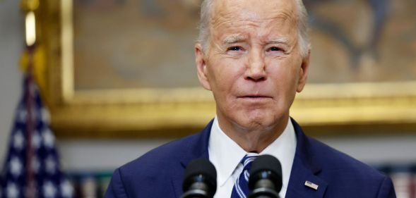 President Joe Biden wears a suit and tie as he stands in front of microphones at the White House