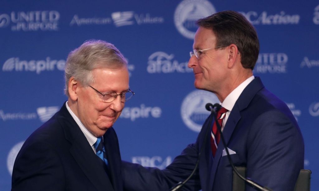 Senator Mitch McConnells wears a suit and tie as he shakes the hand of longtime anti-LGBTQ+ activist Tony Perkins