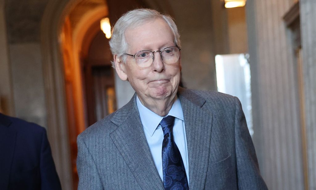 Republican senator Mitch McConnell wears a suit and tie as he walks through a hallway