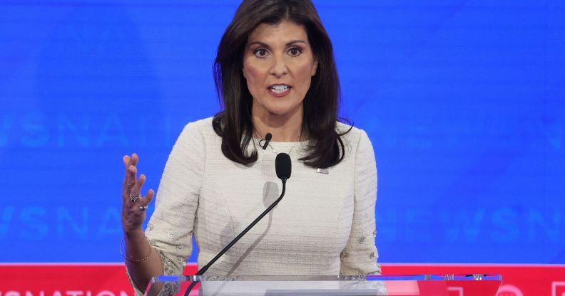 Nikki Haley, who is the top rival to Donald Trump in the 2024 Republican presidential nominee race, wears a white outfit as she speaks into a microphone attached to a podium