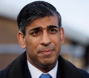 Prime minister Rishi Sunak wears a suit, tie and coat as he stands outside for a photo