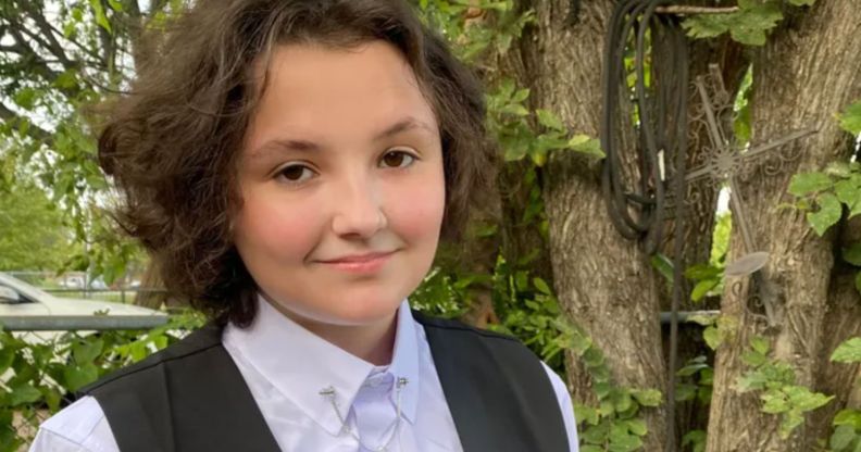 Oklahoma non-binary teen Nex Benedict, who died on 8 February 2024, wears a light coloured shirt and dark vest as they stand outside
