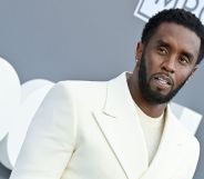 Music mogul Sean "Diddy" Combs wears a white shirt and matching suit while posing for a picture at an event