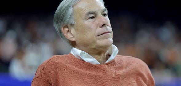 Texas governor Greg Abbott is pictures wearing a light colours shirt and an orange jumper on top