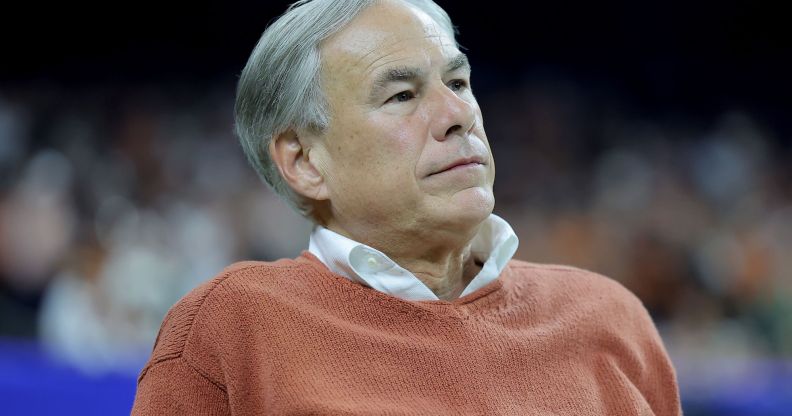 Texas governor Greg Abbott is pictures wearing a light colours shirt and an orange jumper on top