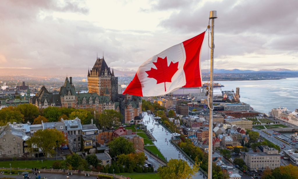 This is an image of the Canadian flag overlooking a small town.