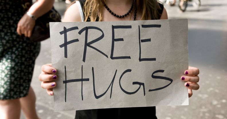 Stock image of a woman holding a sign reading "free hugs"