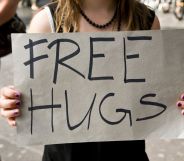 Stock image of a woman holding a sign reading "free hugs"