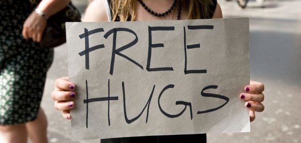 Stock image of a woman holding a sign reading "free hugs"
