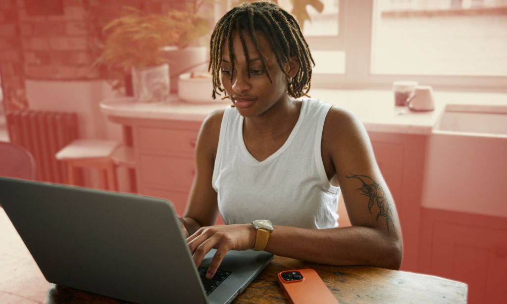 This is an image of a Black person working at a computer. They are wearing a white tank top.