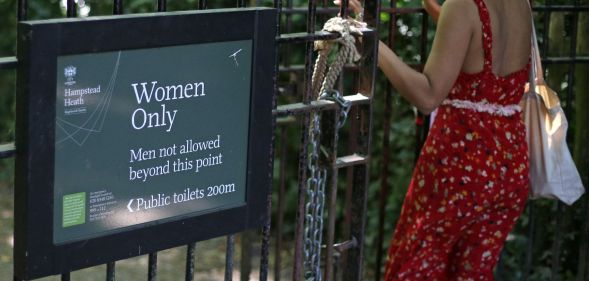A woman walks through the gate of a women-only pond.