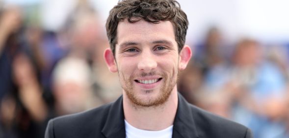 Josh O'Connor in a black blazer and white t-shirt.