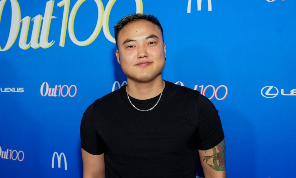 Leo Shang in a black t-shirt and a silver chain stood against a blue background.
