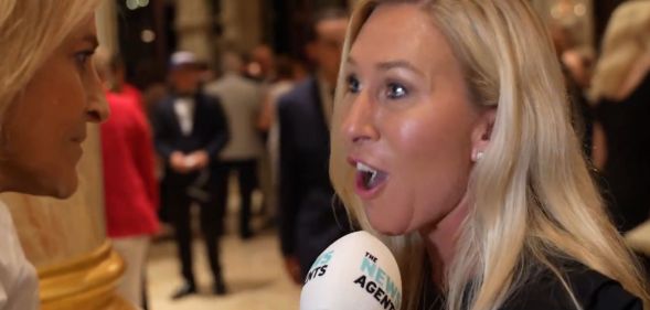 Marjorie Taylor Greene speaking into a microphone looking visibly aggrivated.