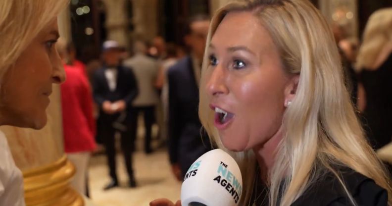 Marjorie Taylor Greene speaking into a microphone looking visibly aggrivated.