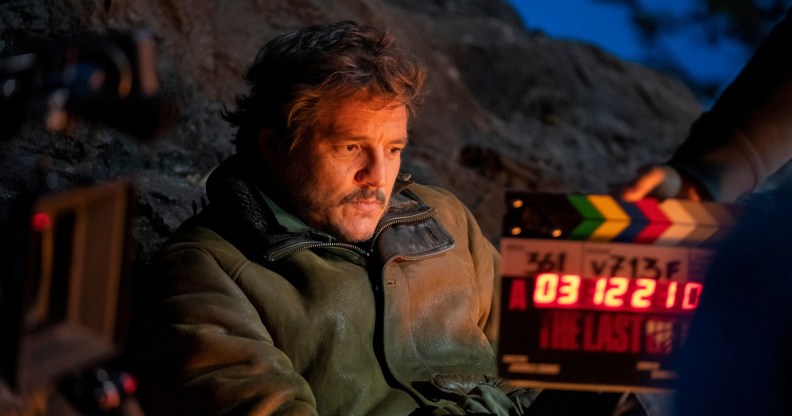 Pedro Pascal sat in a cowboy jacket with a filmling clapper board in front of him.