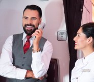 Rylan Clark holding an in-flight phone while working as Virgin Atlantic cabin crew
