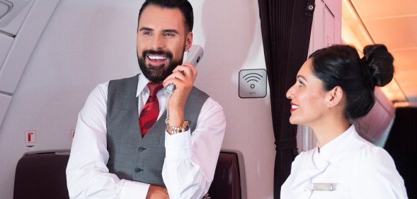 Rylan Clark holding an in-flight phone while working as Virgin Atlantic cabin crew