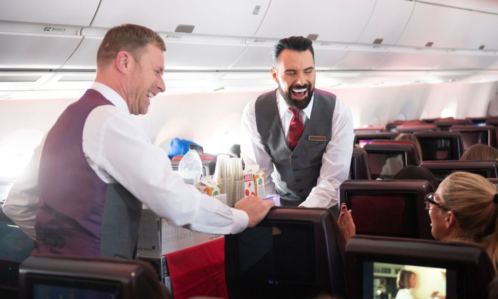 This is an image of Rylan Clark handing out drink on a Virgin Atlantic flight.
