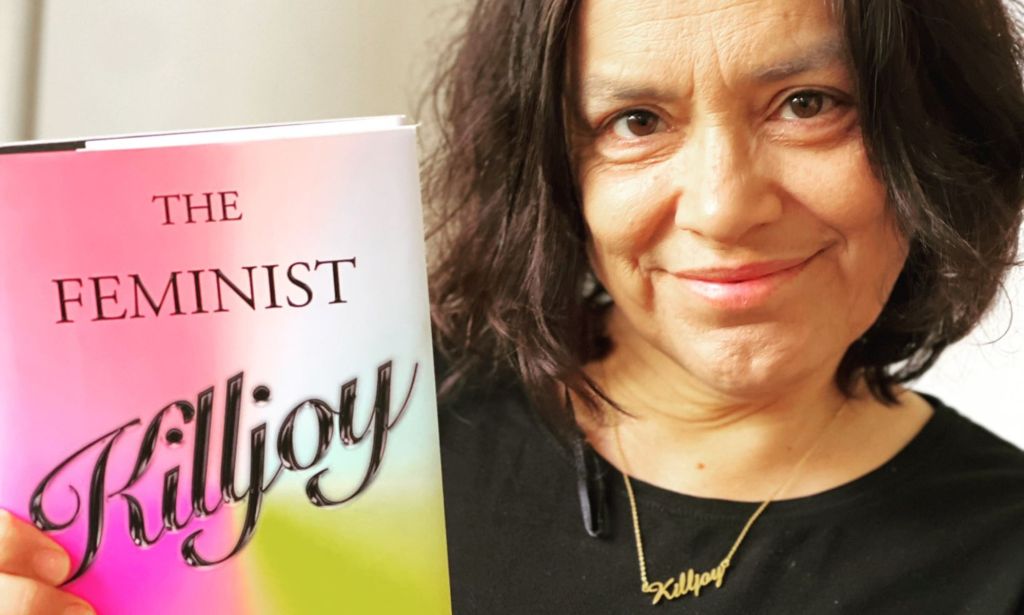 Sara Ahmed pictured holding up her book which reads "The Feminist Killjoy."