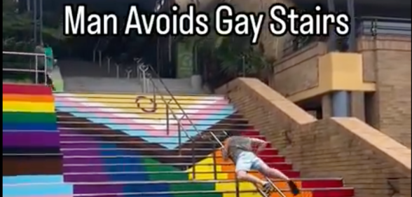 Video captioned 'Man Avoids Gay Stairs' shows man in shorts dragging himself up a metal handrail to avoid walking on stairs painted with the Progress Pride flag in Sydney.