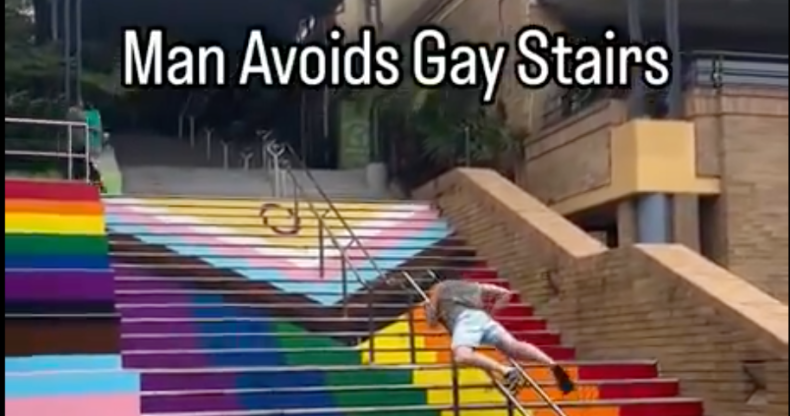 Video captioned 'Man Avoids Gay Stairs' shows man in shorts dragging himself up a metal handrail to avoid walking on stairs painted with the Progress Pride flag in Sydney.