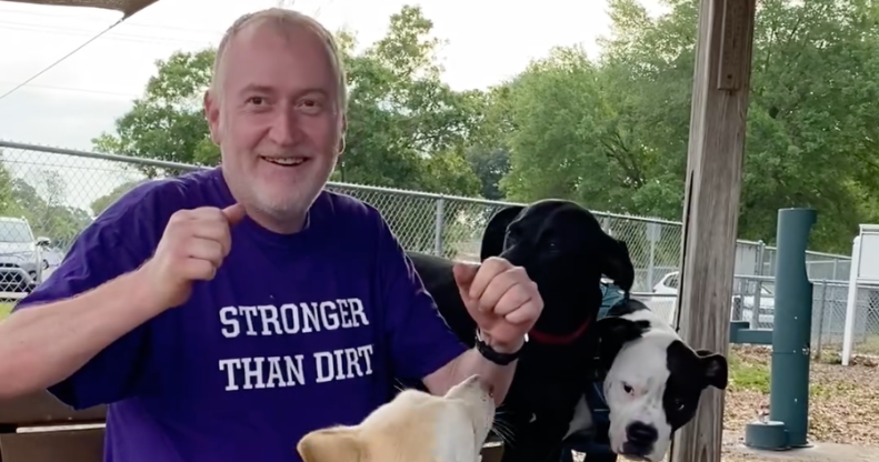 John Walter Lay who was fatally shot at West Dog Park in Tampa, he is wearing a purple shirt that reads 'stronger than dirt' and is surrounded by three dogs.
