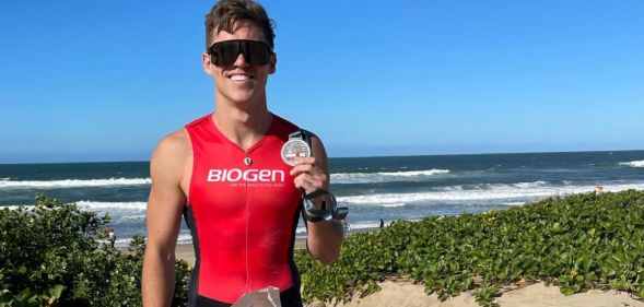 Olympian Sean Gunn poses on a beach with a medal